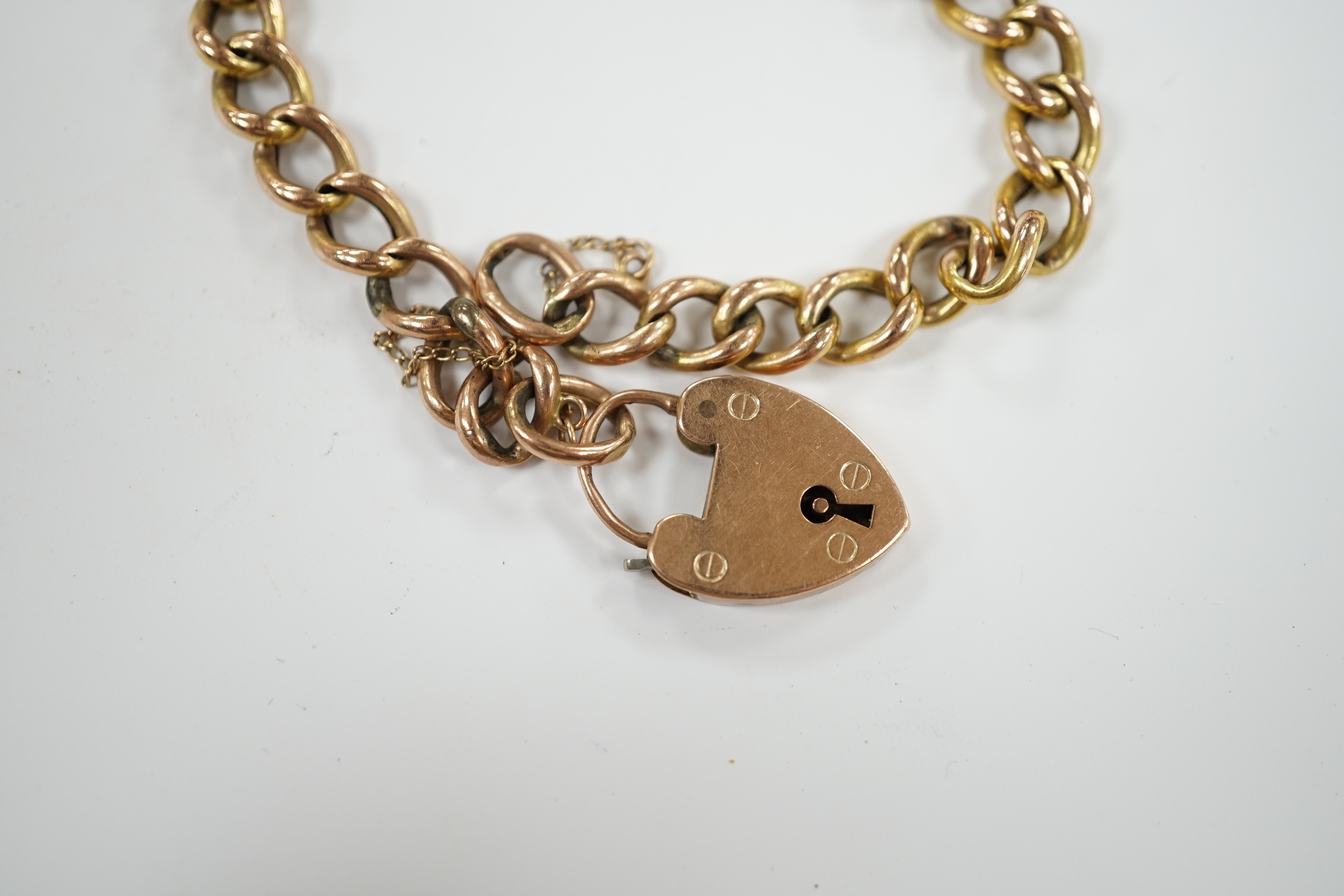 A yellow metal (stamped 9c) curb link bracelet, with heart shaped padlock clasp, hung with a 9ct gold horse charm, 13.9 grams.